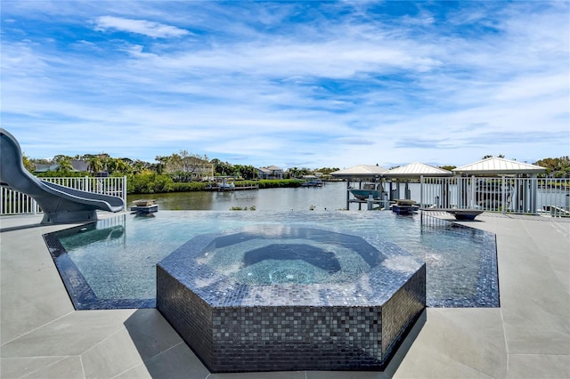 view of pool with a water slide, a water view, a gazebo, and an in ground hot tub