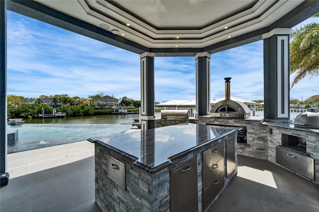 view of patio featuring a water view, a grill, and exterior kitchen