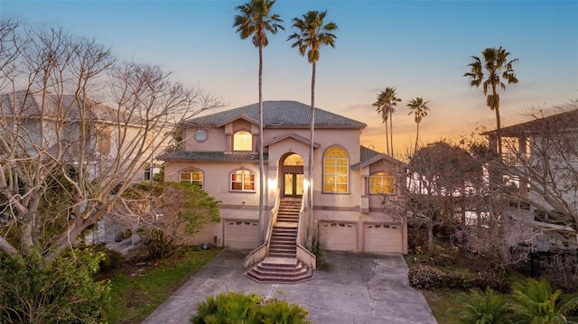 mediterranean / spanish-style house with driveway, french doors, stairway, stucco siding, and a garage