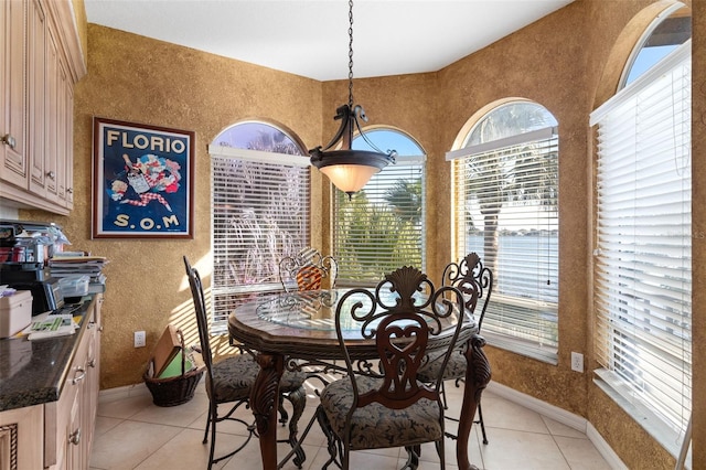 dining room featuring baseboards, light tile patterned floors, and a healthy amount of sunlight
