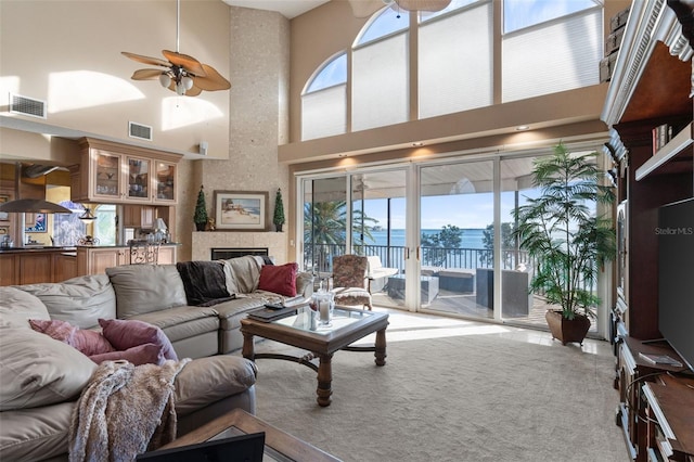 carpeted living area with ceiling fan, visible vents, and plenty of natural light