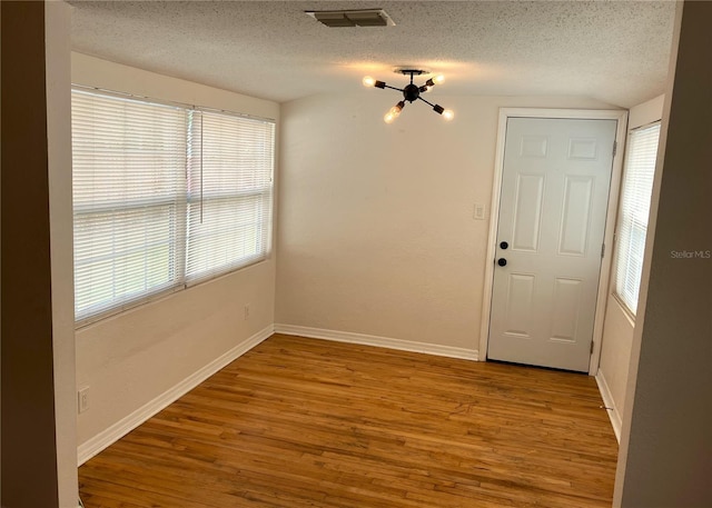 spare room with light hardwood / wood-style floors and a textured ceiling