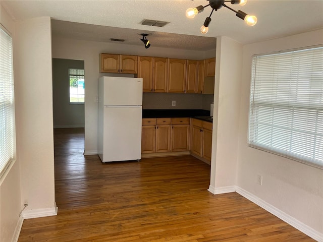 kitchen featuring hardwood / wood-style flooring, white fridge, light brown cabinets, and a textured ceiling