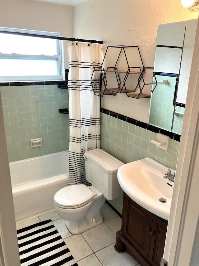 full bathroom with shower / bath combo, tile walls, vanity, tile patterned floors, and toilet