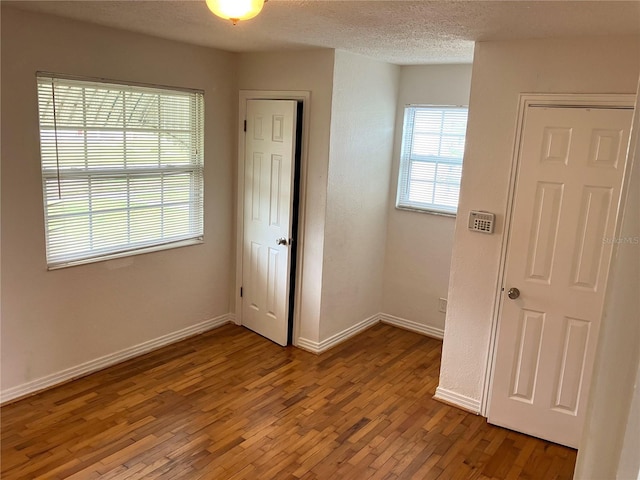 unfurnished room featuring wood-type flooring and a textured ceiling