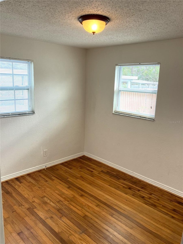 spare room featuring hardwood / wood-style flooring and a textured ceiling