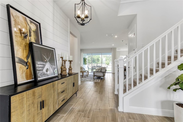 entrance foyer featuring stairs, light wood-type flooring, and a chandelier