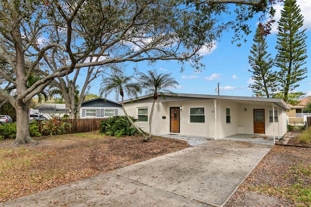 view of front facade with concrete driveway, fence, and a carport