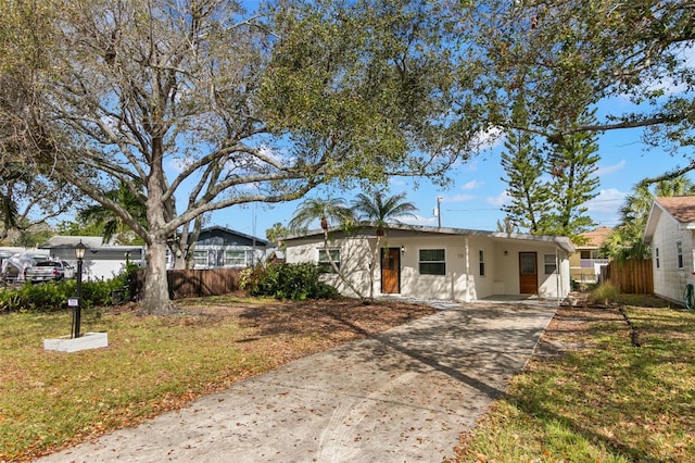 ranch-style home with concrete driveway, a front lawn, fence, and stucco siding