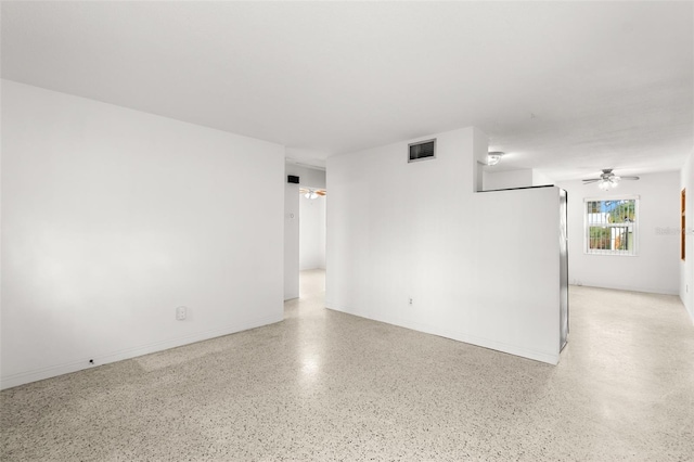 spare room with light speckled floor, visible vents, baseboards, and a ceiling fan