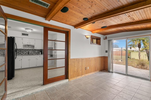 empty room featuring wooden ceiling, a wainscoted wall, visible vents, and beam ceiling