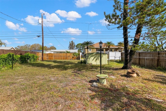 view of yard featuring an outbuilding, a fenced backyard, and a shed