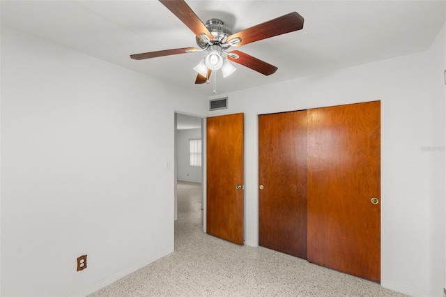 unfurnished bedroom featuring baseboards, visible vents, ceiling fan, light speckled floor, and a closet