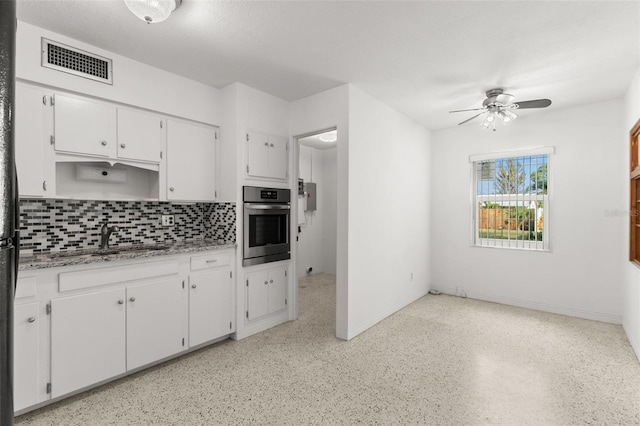 kitchen with visible vents, decorative backsplash, white cabinets, a sink, and oven