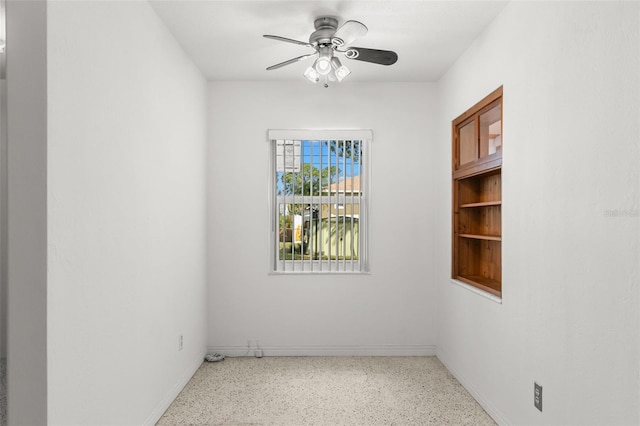 spare room with speckled floor, a ceiling fan, and baseboards