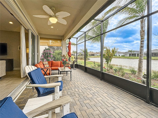 sunroom / solarium featuring a ceiling fan and a water view