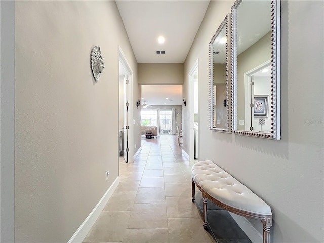 hallway with visible vents, light tile patterned floors, and baseboards