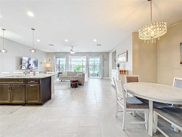 kitchen featuring light countertops, open floor plan, a sink, decorative light fixtures, and dark brown cabinetry