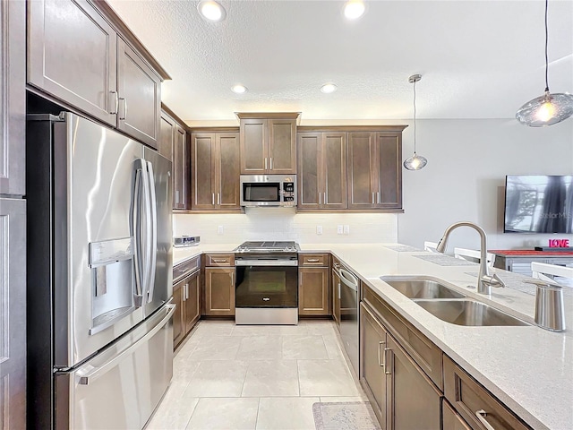 kitchen featuring stainless steel appliances, hanging light fixtures, tasteful backsplash, and a sink