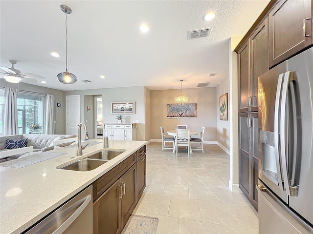 kitchen featuring a sink, open floor plan, visible vents, pendant lighting, and stainless steel appliances