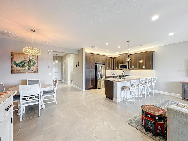 kitchen with light countertops, a breakfast bar, stainless steel appliances, and pendant lighting