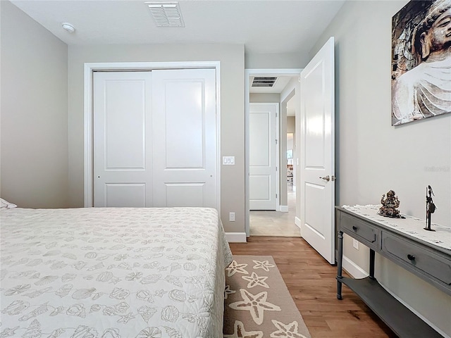 bedroom with light wood-style flooring, visible vents, a closet, and baseboards