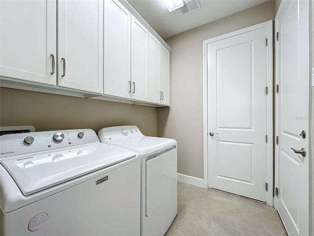 washroom featuring baseboards, visible vents, washing machine and clothes dryer, and cabinet space