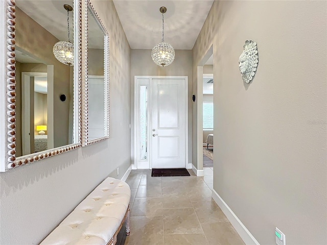 tiled foyer featuring baseboards and a chandelier