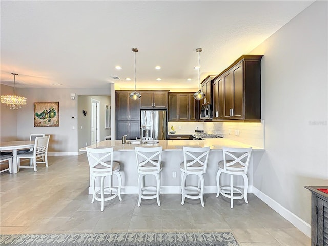 kitchen with appliances with stainless steel finishes, dark brown cabinets, a chandelier, and light countertops