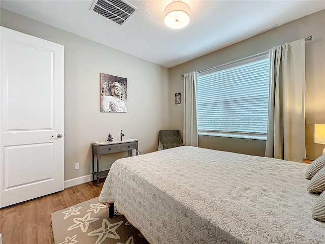 bedroom featuring light wood-style flooring, visible vents, and baseboards