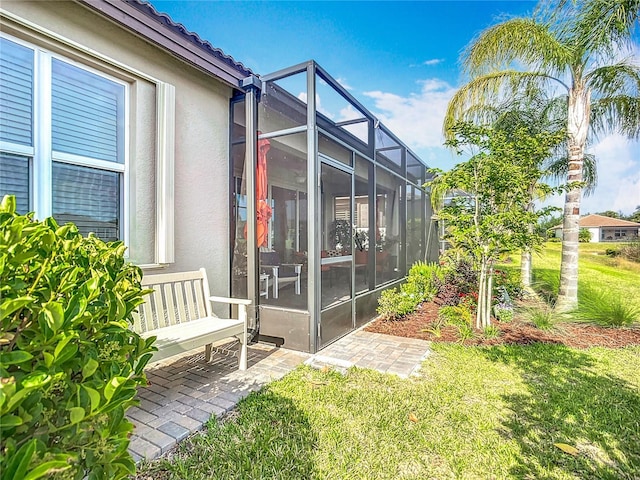 exterior space featuring a tile roof, a lanai, a yard, and stucco siding