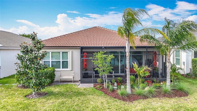 rear view of property with stucco siding, a sunroom, a tiled roof, and a lawn
