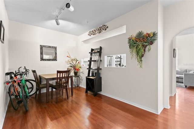 dining space with hardwood / wood-style flooring and rail lighting