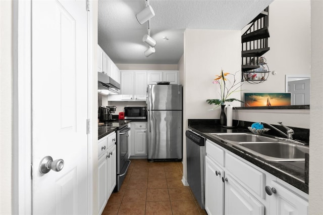 kitchen featuring appliances with stainless steel finishes, sink, white cabinets, and dark tile patterned floors