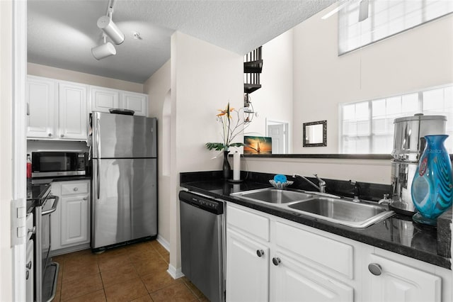 kitchen featuring stainless steel appliances, sink, dark tile patterned flooring, a textured ceiling, and white cabinets