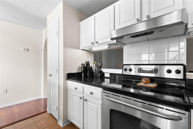 kitchen with light tile patterned flooring, stainless steel electric stove, a textured ceiling, and white cabinets