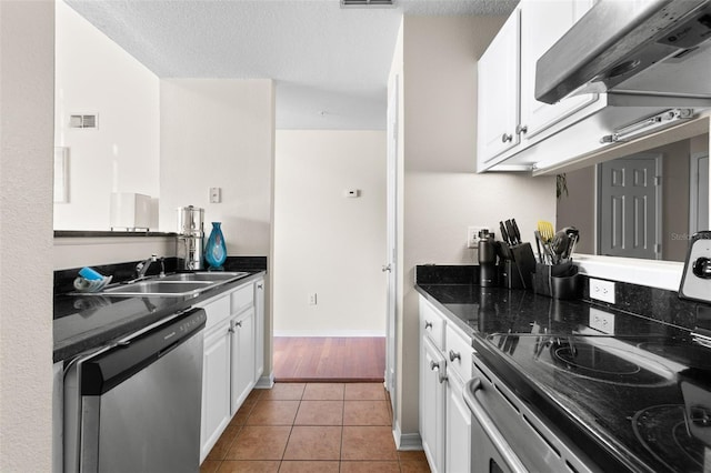 kitchen featuring sink, light tile patterned flooring, range hood, stainless steel appliances, and white cabinets