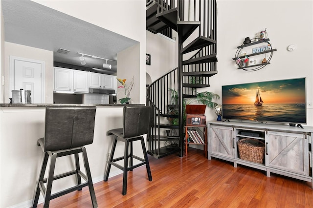 kitchen featuring a breakfast bar area, decorative backsplash, wood-type flooring, and white cabinets