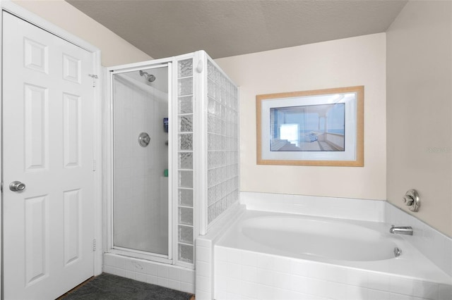 bathroom featuring a textured ceiling and shower with separate bathtub