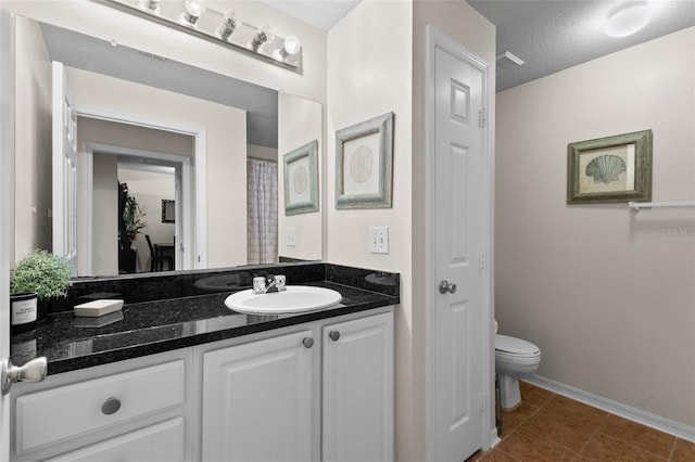 bathroom featuring tile patterned floors, toilet, vanity, and a textured ceiling