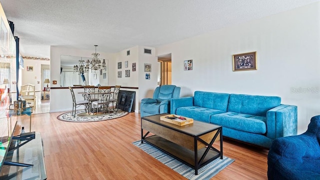 living room featuring hardwood / wood-style flooring, an inviting chandelier, and a textured ceiling