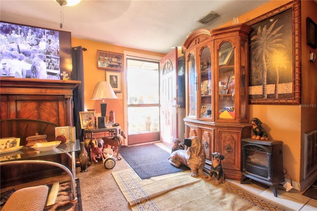 sitting room with a wood stove and light colored carpet