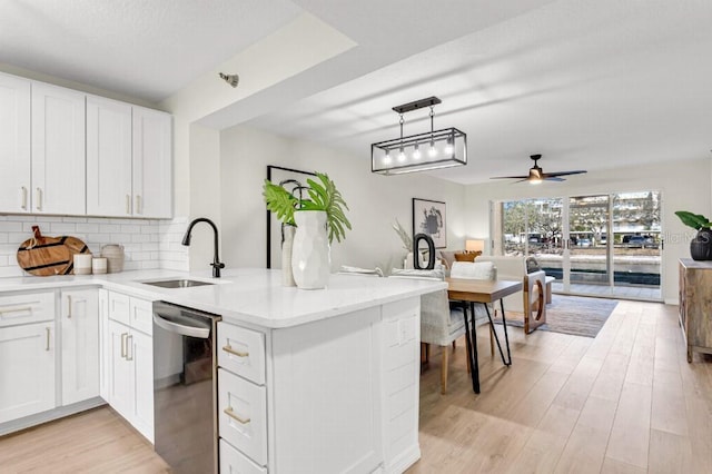 kitchen featuring white cabinets, sink, stainless steel dishwasher, and kitchen peninsula