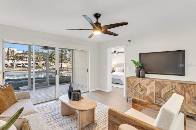 living room featuring ceiling fan, a water view, and light hardwood / wood-style floors