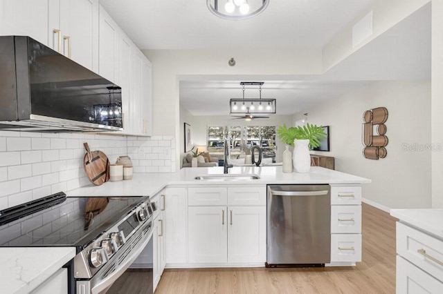 kitchen with kitchen peninsula, stainless steel appliances, sink, white cabinets, and pendant lighting