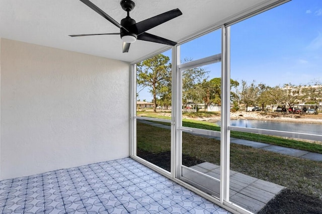 unfurnished sunroom featuring a water view and ceiling fan