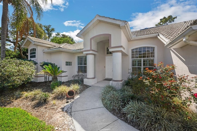 property entrance featuring a tile roof and stucco siding