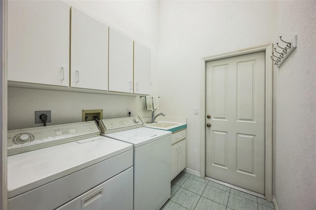 washroom with cabinet space, a sink, washing machine and clothes dryer, and light tile patterned floors