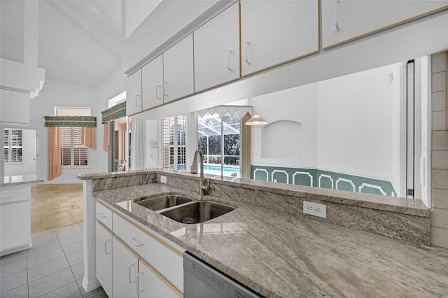 kitchen featuring light stone counters, white cabinets, and a sink