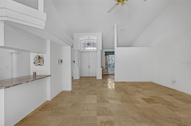 entryway with lofted ceiling, stone finish floor, and a ceiling fan